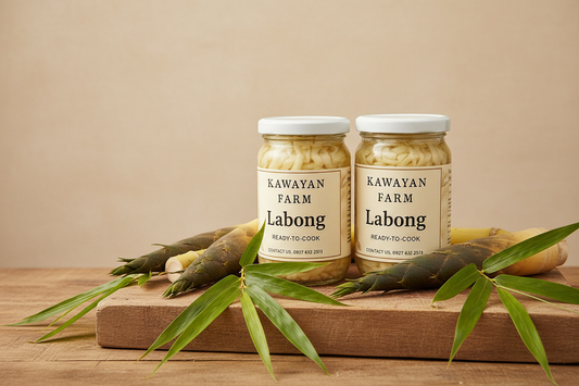 Two Kawayan Farm Labong Ready-to-Cook glass jars on a rustic wooden surface with fresh bamboo shoots and green bamboo leaves beside them