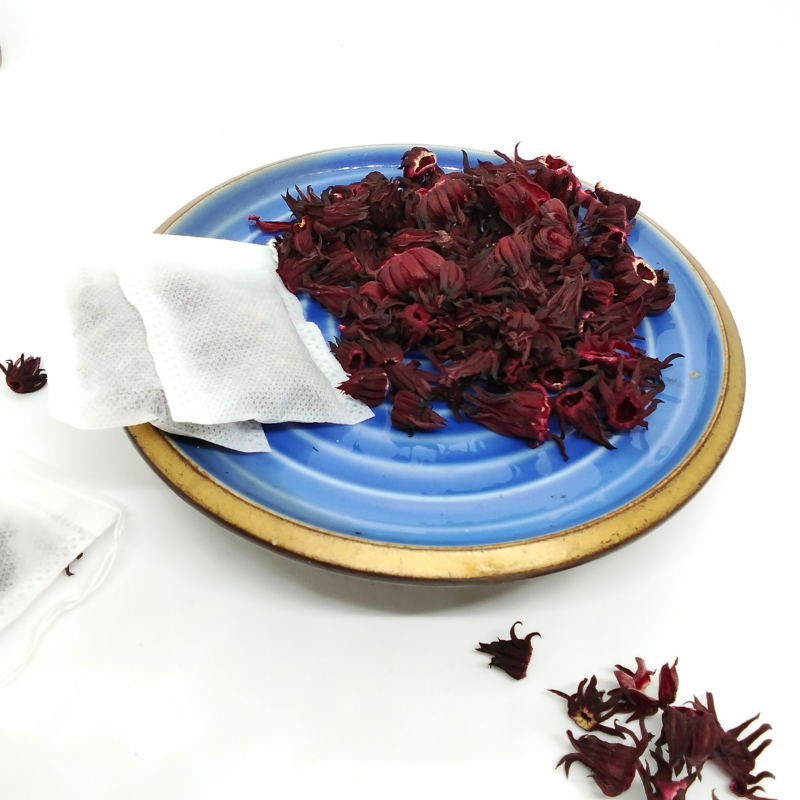 Dried Roselle petals and Roselle tea bags in blue plate